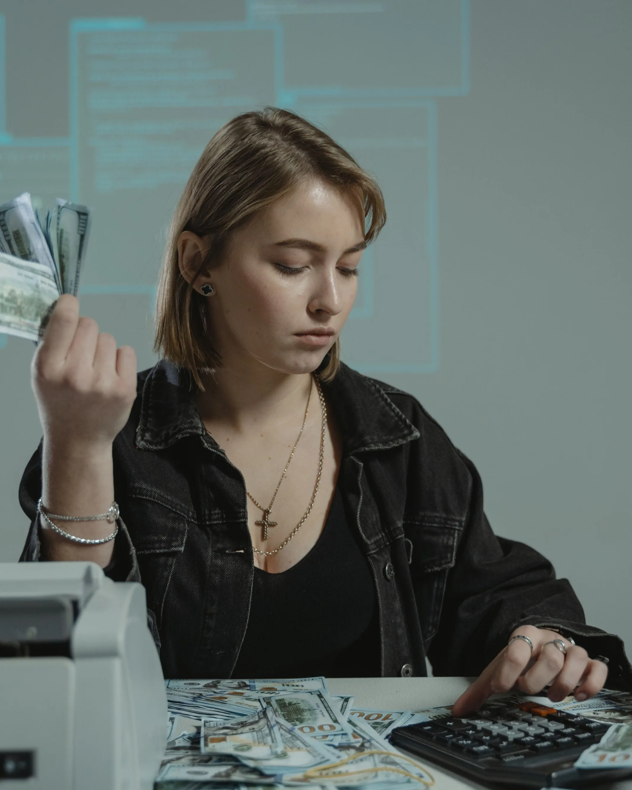 Une femme relit son relevé de frais bancaires à sa table, calculatrice et carte bancaire posées devant elle